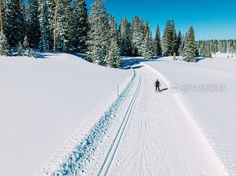 广角航拍跟随一个越野滑冰滑雪者在科罗拉多的Grand Mesa国家森林的一条修整过的小道上滑雪